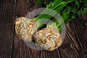 Celeriac roots with green leaves on dark wooden boards photo