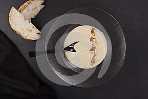 Celery cream soup in black plate over dark background from above