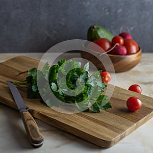 Celery leaves lie on a wooden cutting board