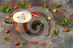 Celery root soup in copper cup on dark background.