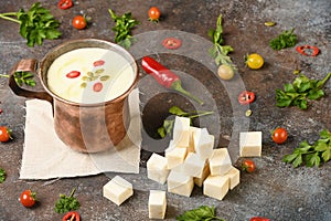 Celery root soup in copper cup on dark background.