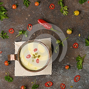 Celery root soup in copper cup on dark background.
