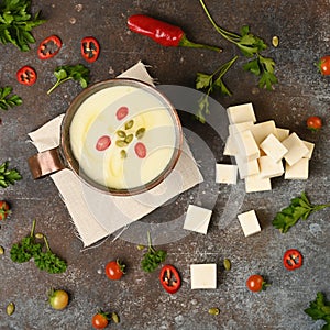 Celery root soup in copper cup on dark background.