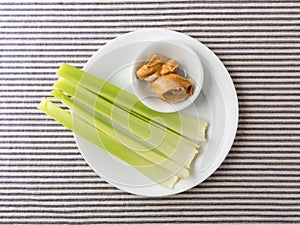 Celery stalks with peanut butter on a white plate