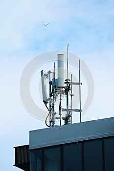 Cell Phone Antennas on the Rooftop with Airplane Flying on Sky