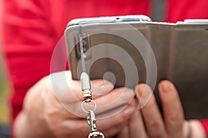 Cell phone in a leather case with a chain in the hands of woman