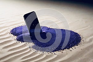 A cell phone lies hidden in a mound of electric blue sand