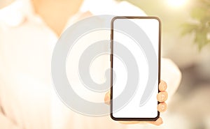 Cell phone mockup. woman in white clothes shows blank white cell phone screen. Mobile phone with white screen in female hand