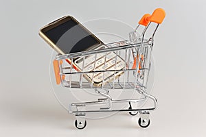 Cell phone in supermarket pushcart on gray background photo