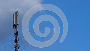 Cell site antenna on a blue sky and white clouds background. Cell tower with mobile Telecommunications equipment. Cellular tower