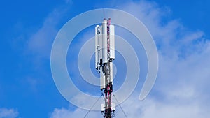 Cell site antenna on a blue sky and white clouds background. Cell tower with mobile Telecommunications equipment. Cellular tower