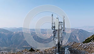 Cell tower. Mobile phone antenna aerial view. Rocky mountain and blue sky
