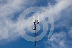 A cell tower set against a blue sky, a modern silver metal construction with white panels to keep your phone signal uninterrupted