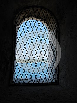 Cell wall with a window with bars with sea view, interior perspective