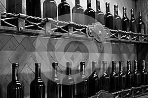 Cellar shelves with dark corked wine bottles against wooden wall black and white monochrome.