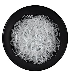 Cellophane or glass noodles in black matte plate isolated on a white background, top view