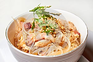 Cellophane noodles with chicken and bacon in a light plate