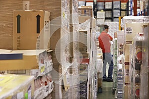 Cellophane Wrapped Goods With Man In Background At Warehouse