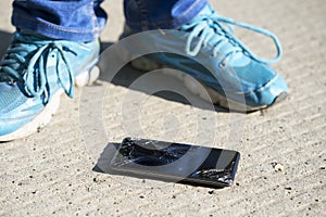 Cellphone with broken screen is on the concrete floor after falling down