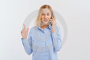 Cellphone, cellular concept. Smiling happy blonde woman talking on mobile phone, gestures with hand, pointing finger up, showing