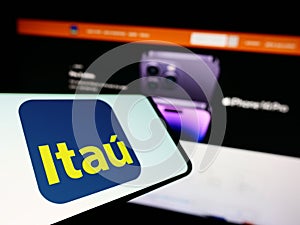 Cellphone with logo of Brazilian company Itau Unibanco Holding S.A. on screen in front of business website.