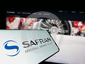 Cellphone with logo of French aerospace company Safran S.A. on screen in front of business website.