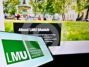 Cellphone with logo of German university Ludwig-Maximilians-UniversitÃÂ¤t MÃÂ¼nchen on screen in front of website.