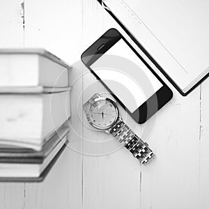 Cellphone with stack of book and watch black and white tone colo