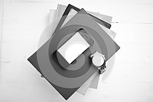 Cellphone with stack of book and watch black and white tone colo