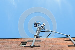 Cellular antenna on the roof of a brick house on blue sky background.