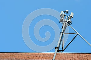 Cellular antenna on the roof of a brick house on blue sky background,space for text.