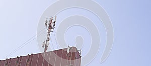Cellular antenna on the roof of a high building on blue sky background.