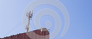 Cellular antenna on the roof of a high building on blue sky background.