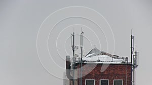 Cellular antennas on the roof of a residential house covered with snow