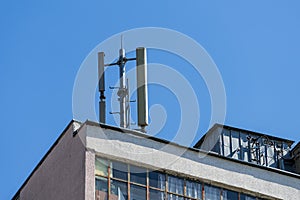 Cellular communication antenna on a flat roof of a multi-storey apartment building against blue sky on a sunny day