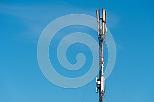 a cellular communication antenna installed on the roof of a high-rise building against a blue sky background. 5G radio network