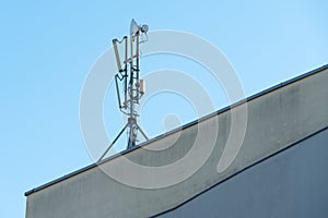 a cellular communication antenna installed on the roof of a high-rise building against a blue sky background. 5G radio network