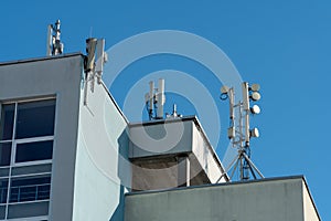 a cellular communication antenna installed on the roof of a high-rise building against a blue sky background. 5G radio network