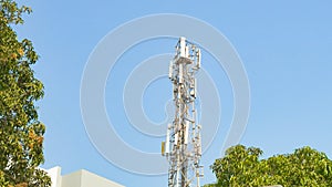 cellular communication tower against the backdrop of the sky and trees