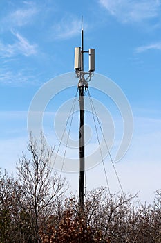 Cellular communication tower with antennas against blue sky