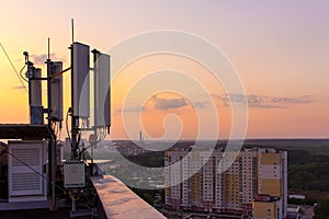 Cellular communications tower on a background of the city and a beautiful sunset in summer