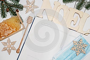 Cellular honey in wooden frame near empty notebook for records. Christmas background with branches of New Year's spruce