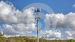 Cellular, mobile phone transmitter tower with blue sky and clouds middle