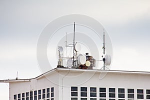 Cellular signal receiving stations and satellite dishes on the roof of a high-rise residential building.