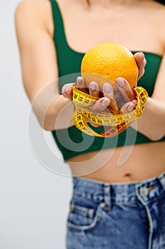Cellulite is consequence of poor nutrition. Nutritionist holding measuring tape with orange fruit, panorama