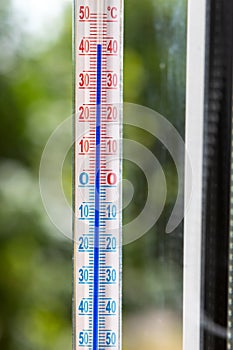 A Celsius thermometer on a window frame shows high temperatures of 43 degrees during an abnormal heat outside.