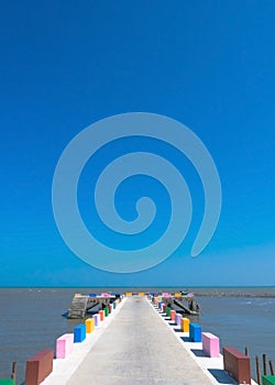 The cement bridge extends into the sea. With colorful barrier panels In the blue sky
