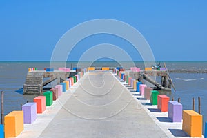 The cement bridge extends into the sea. With colorful barrier panels In the blue sky