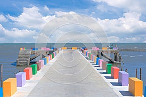 The cement bridge extends into the sea. With colorful barrier panels In the blue sky