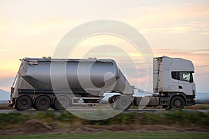 Cement cargo truck driving on highway hauling construction products. Delivery transportation and logistics concept